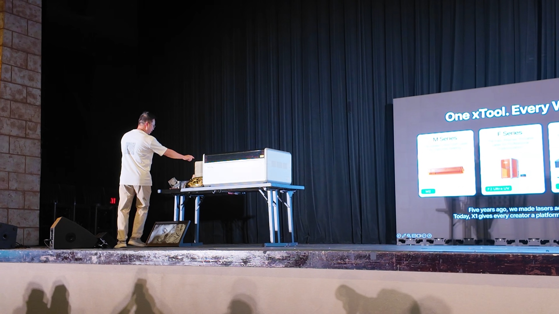 xTool X1 prototype on stage viewed from the rear with a white source backpack installed